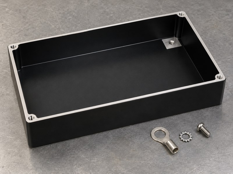 black anodized aluminum heat sink: black anodized enclosure tray with a bare gasket rim and a small grounding pad