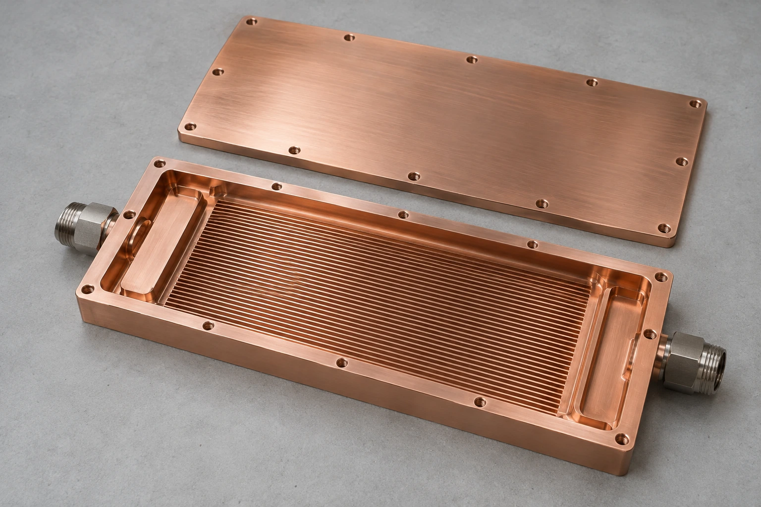 Open copper cold plate showing parallel channels and inlet and outlet header regions with the matching lid removed