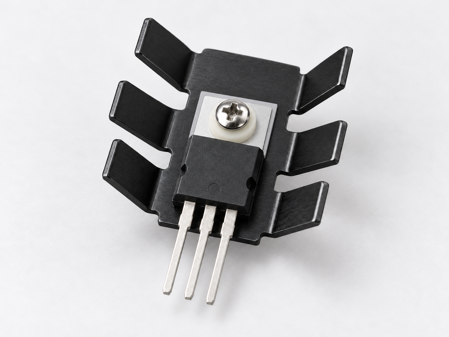 TO-220 device clamped to a six-finger stamped heat sink with insulating mounting hardware.